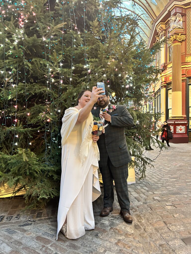 Mary and Martin taking a selfie in front of a christmas tree at Leadenhall Market 